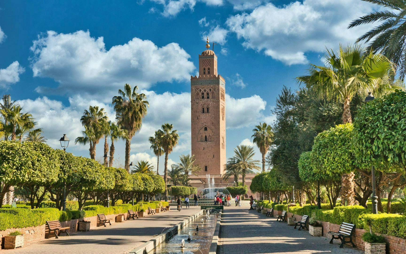 Koutoubia Mosque tower in Marrakech with surrounding gardens and palm trees.