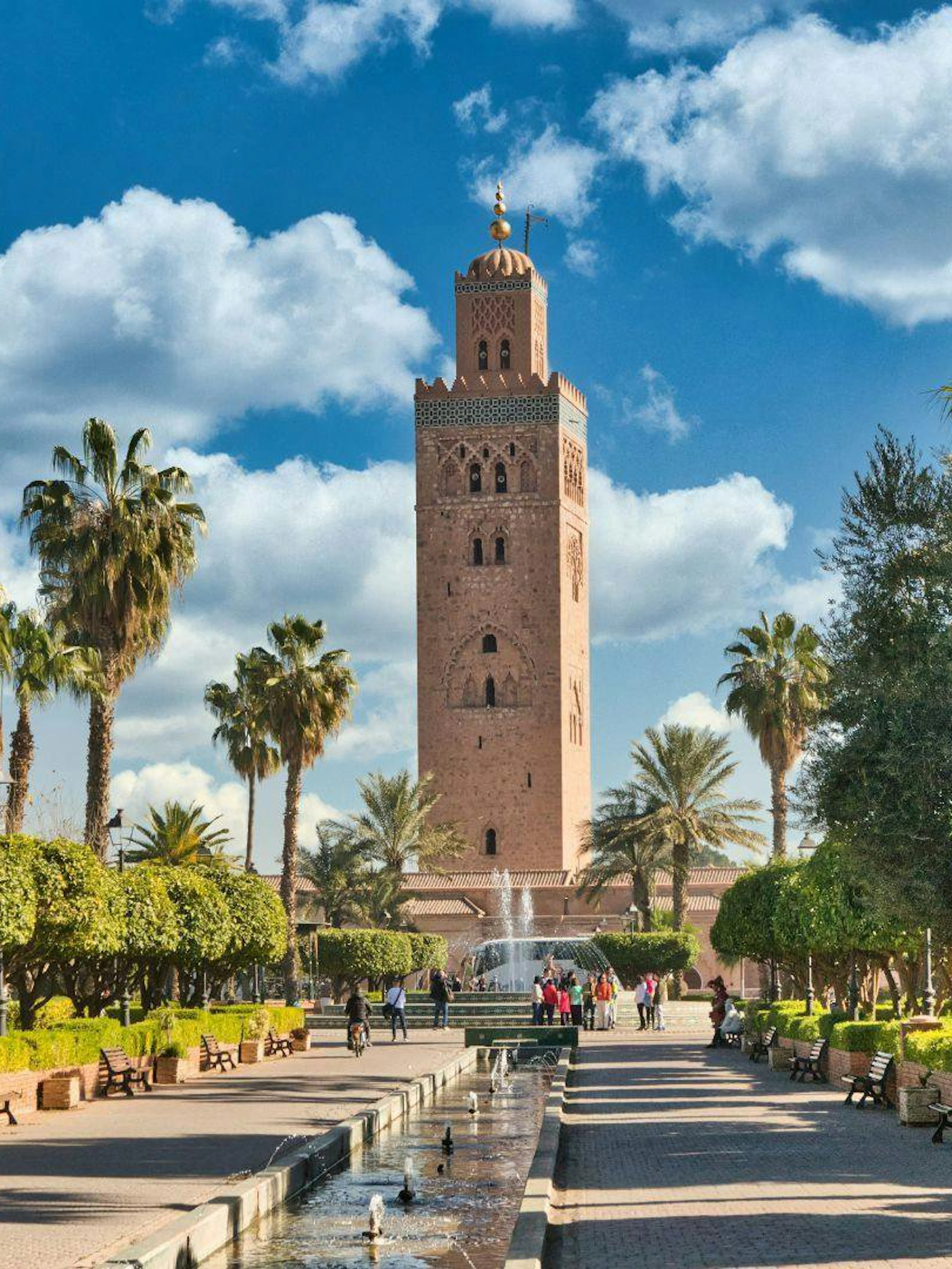 Koutoubia Mosque tower in Marrakech with surrounding gardens and palm trees.