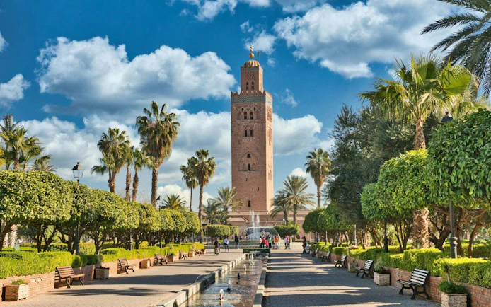 Koutoubia Mosque tower in Marrakech with surrounding gardens and palm trees.