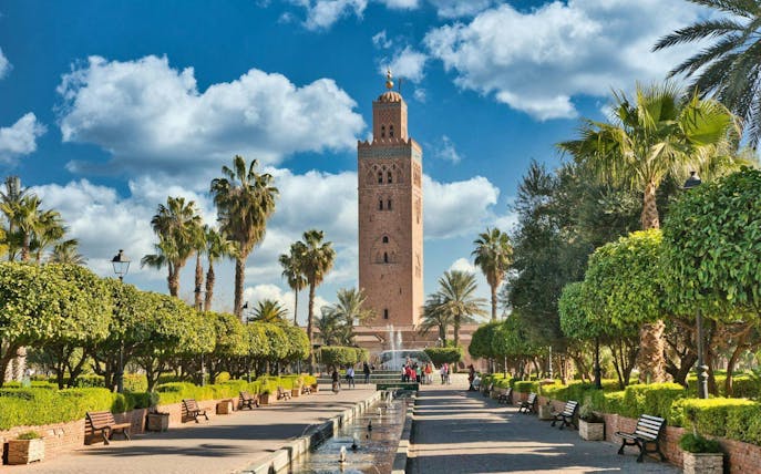 Koutoubia Mosque tower in Marrakech with surrounding gardens and palm trees.