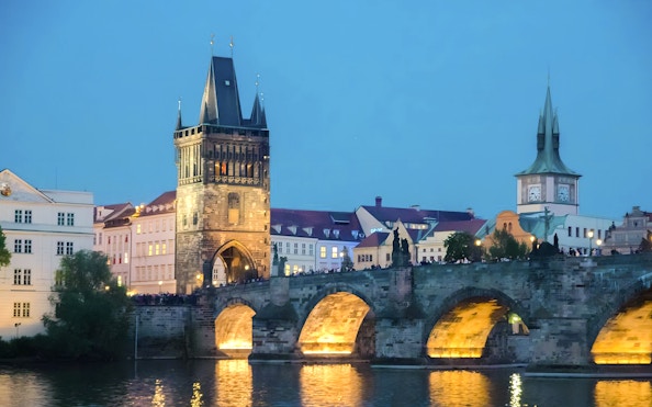 Charles Bridge illuminated at dusk in Prague, ideal for an evening dinner cruise with live music.