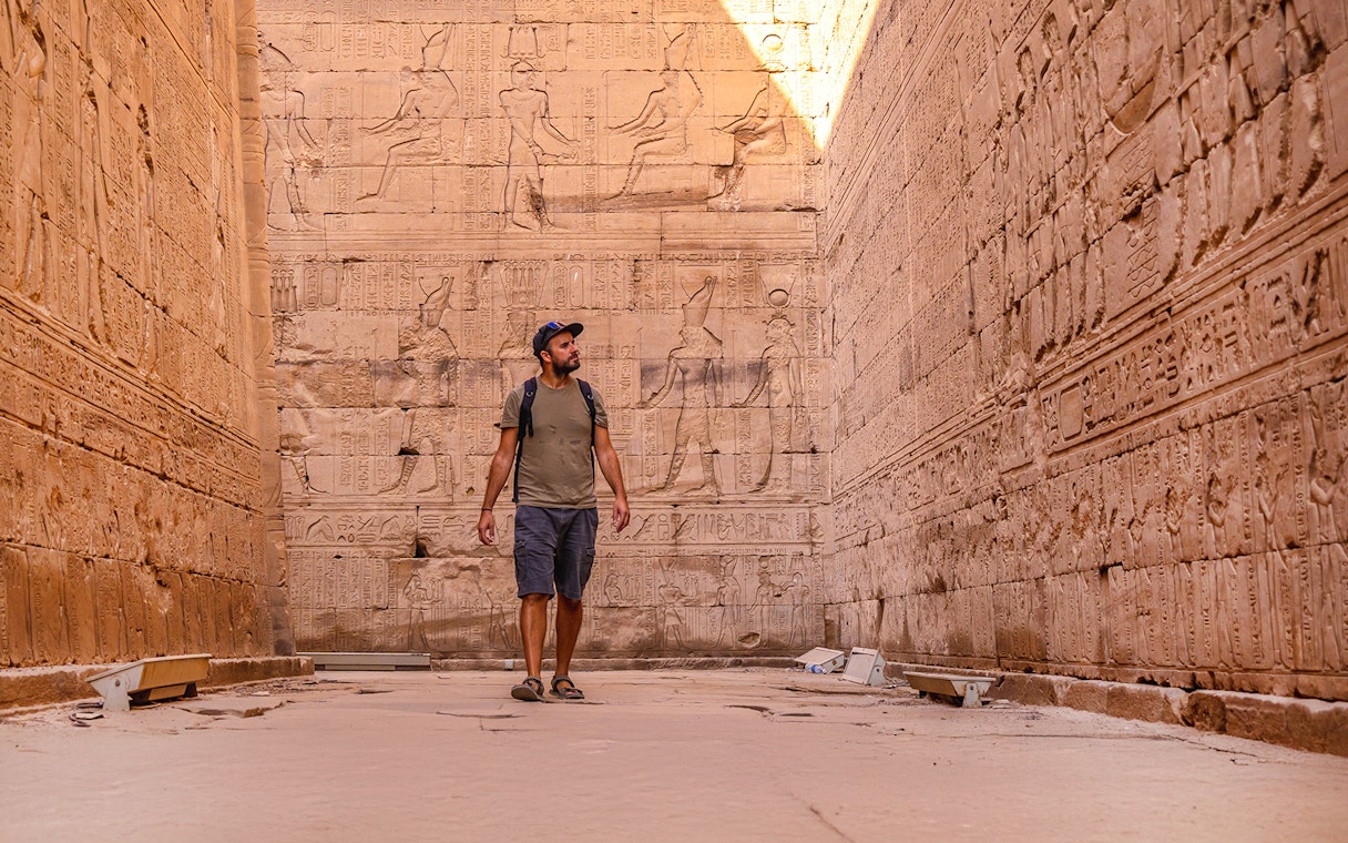Man admiring Egyptian relief sculptures at Temple of Horus, Edfu.