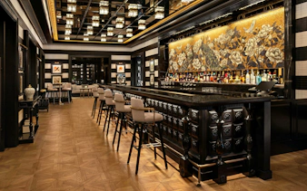 Upscale bar interior with dark wood paneling and black marble counter at Resorts World Sentosa Singapore.