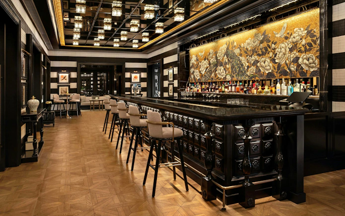 Upscale bar interior with dark wood paneling and black marble counter at Resorts World Sentosa Singapore.