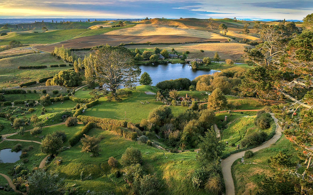 Hobbiton Movie Set landscape with lush greenery and winding paths, seen on Auckland private tour.