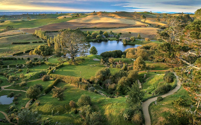 Hobbiton Movie Set landscape with lush greenery and winding paths, seen on Auckland private tour.