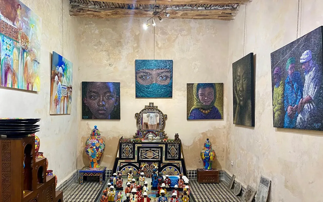 Essaouira art gallery with colorful paintings and traditional Moroccan pottery on display.