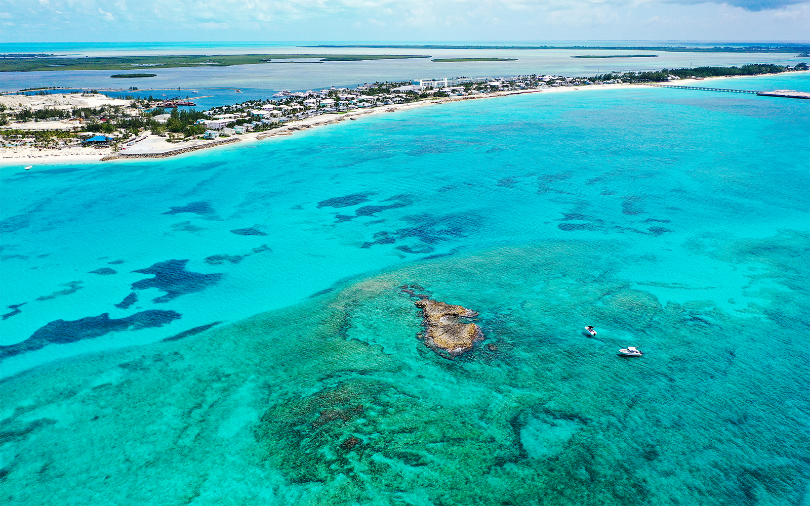 Aerial view of boats near coral rocks with North Bimini coast in the background.