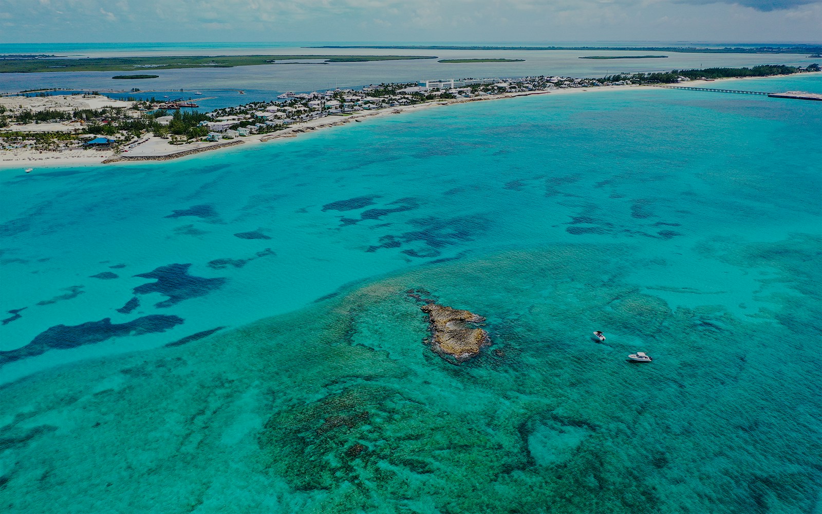 Aerial view of boats near coral rocks with North Bimini coast in the background.