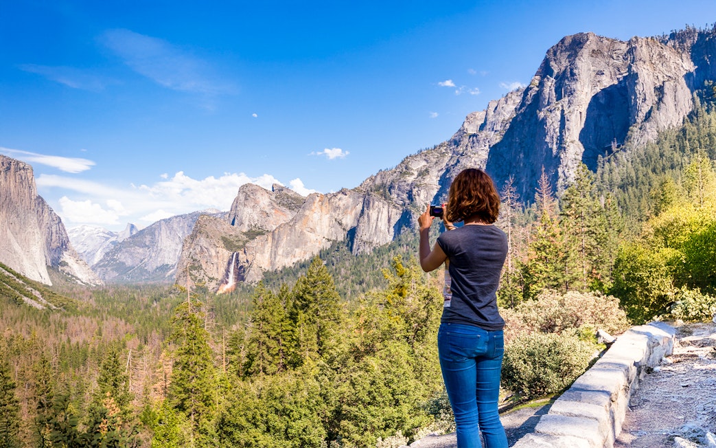 Young woman photographing Yosemite Valley from Tunnel View, Yosemite National Park, USA.