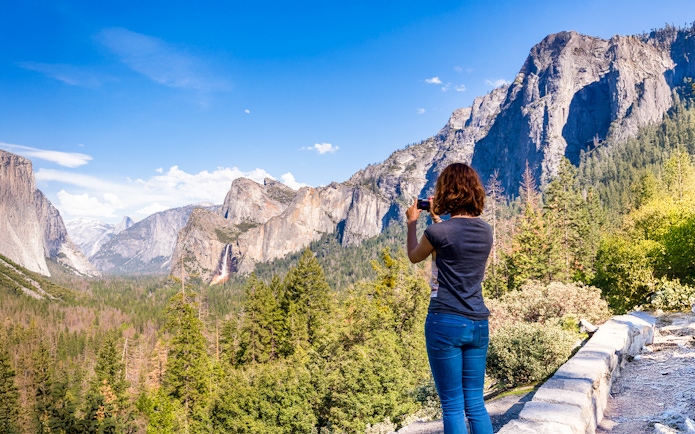 Young woman photographing Yosemite Valley from Tunnel View, Yosemite National Park, USA.