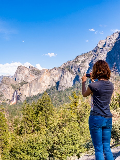 Young woman photographing Yosemite Valley from Tunnel View, Yosemite National Park, USA.