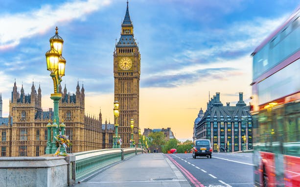 Big Ben and Westminster Bridge at sunset in London with a passing double-decker bus.