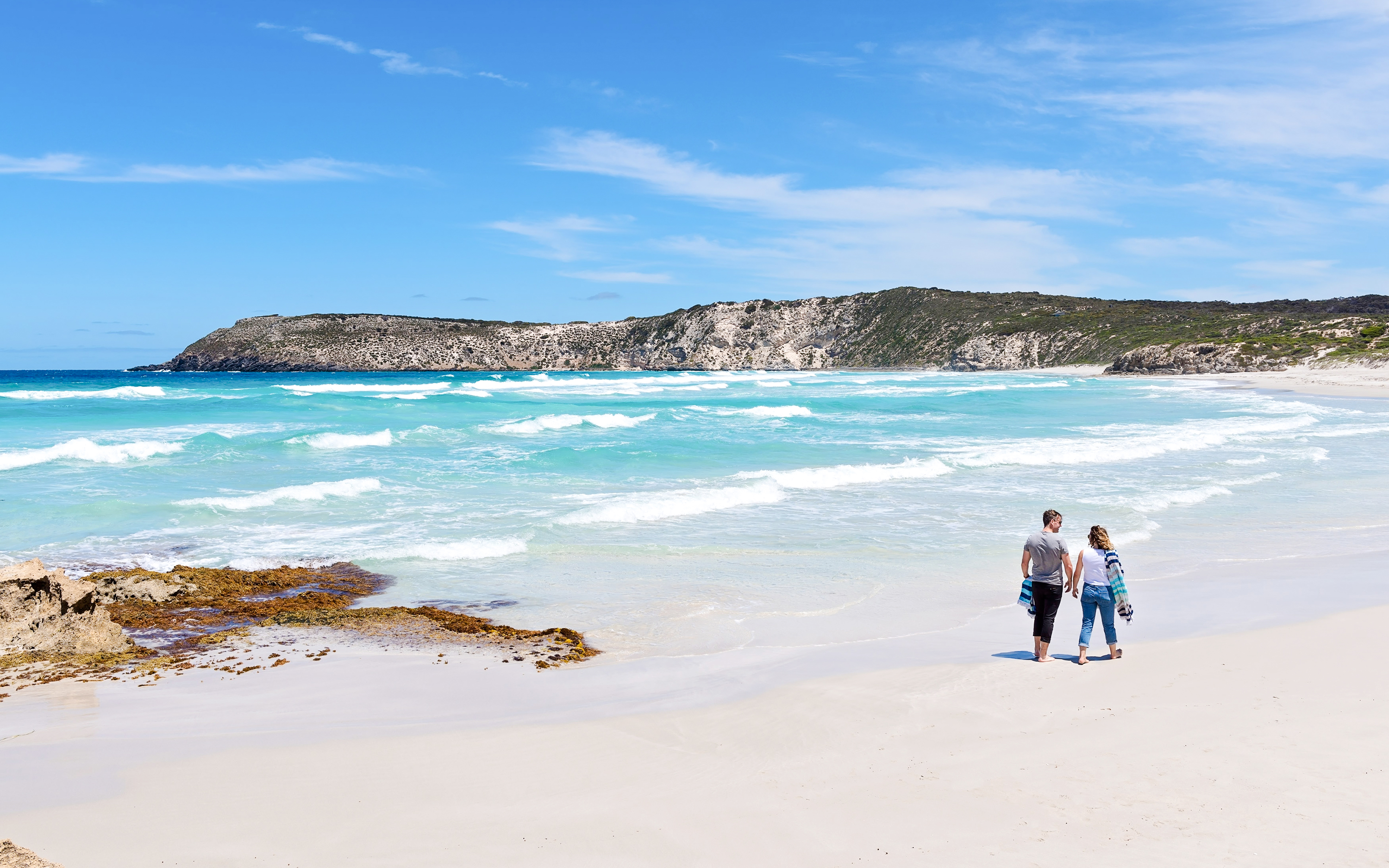 Couple walking along the shoreline at Kangaroo Island beach, Australia.