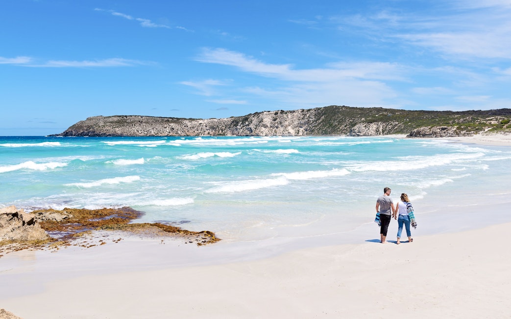 Couple walking along the shoreline at Kangaroo Island beach, Australia.
