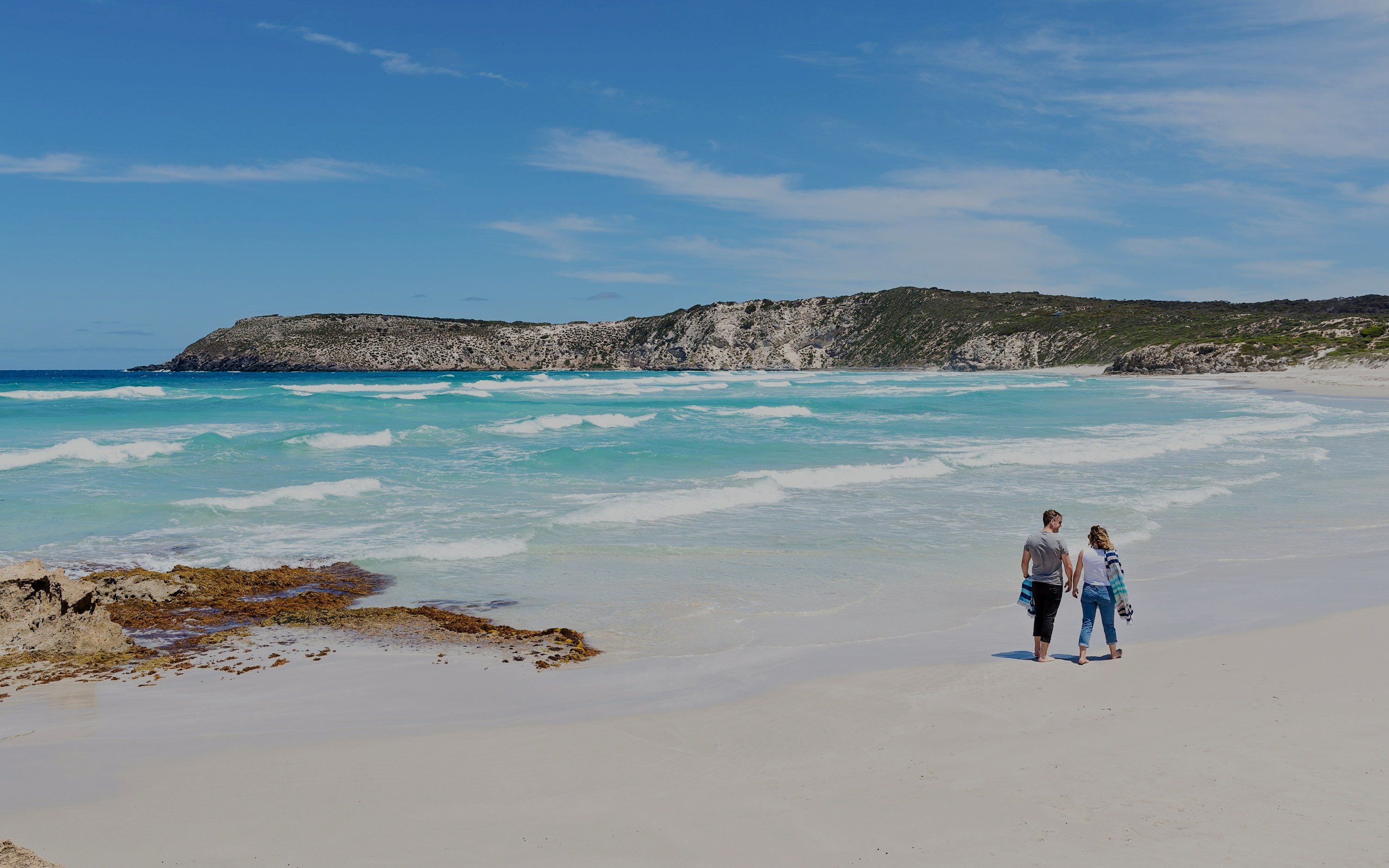 Couple walking along the shoreline at Kangaroo Island beach, Australia.
