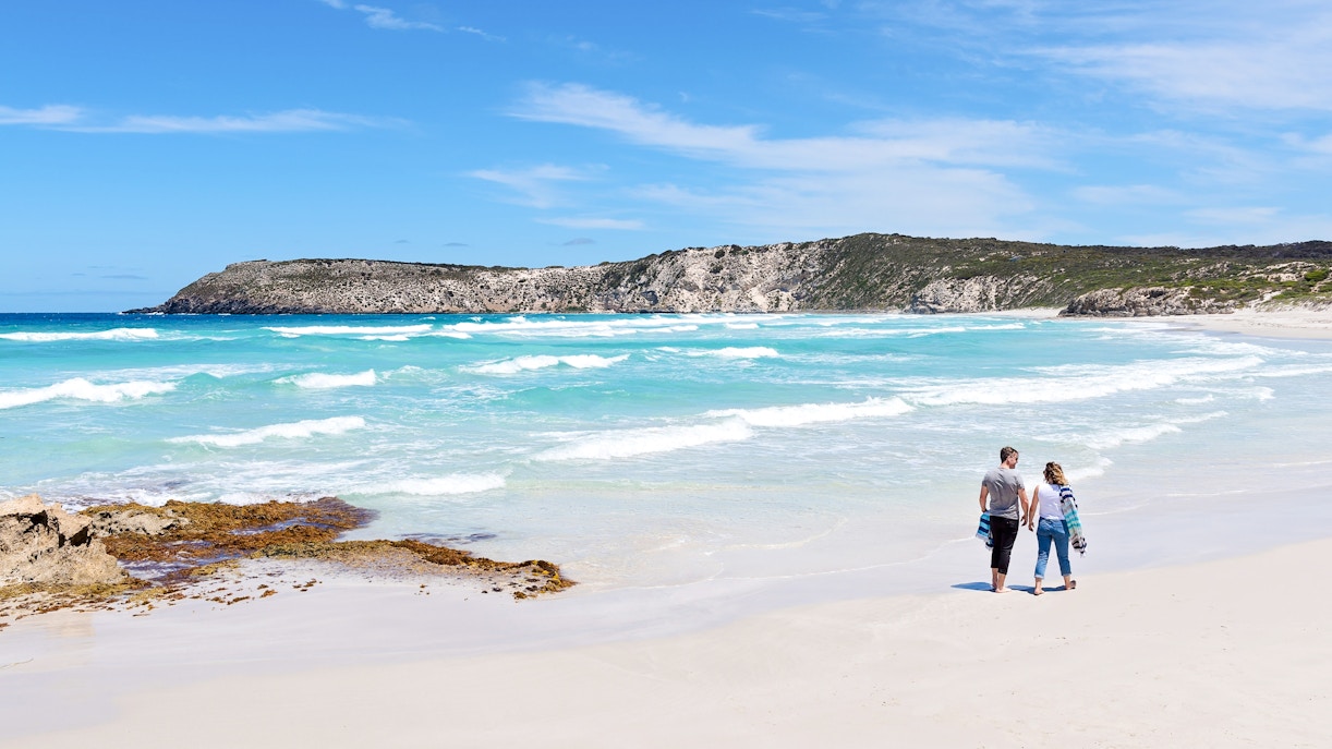 Couple walking along the shoreline at Kangaroo Island beach, Australia.