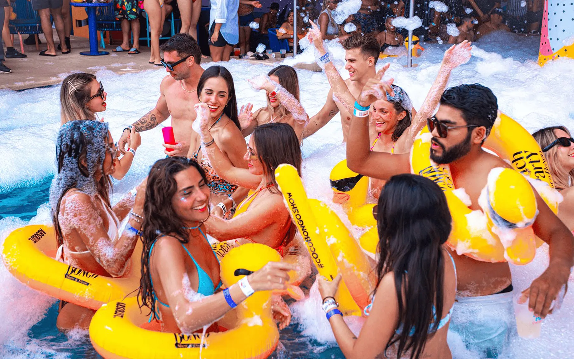 People enjoying foam party at Coco Bongo Beach with inflatable rings.