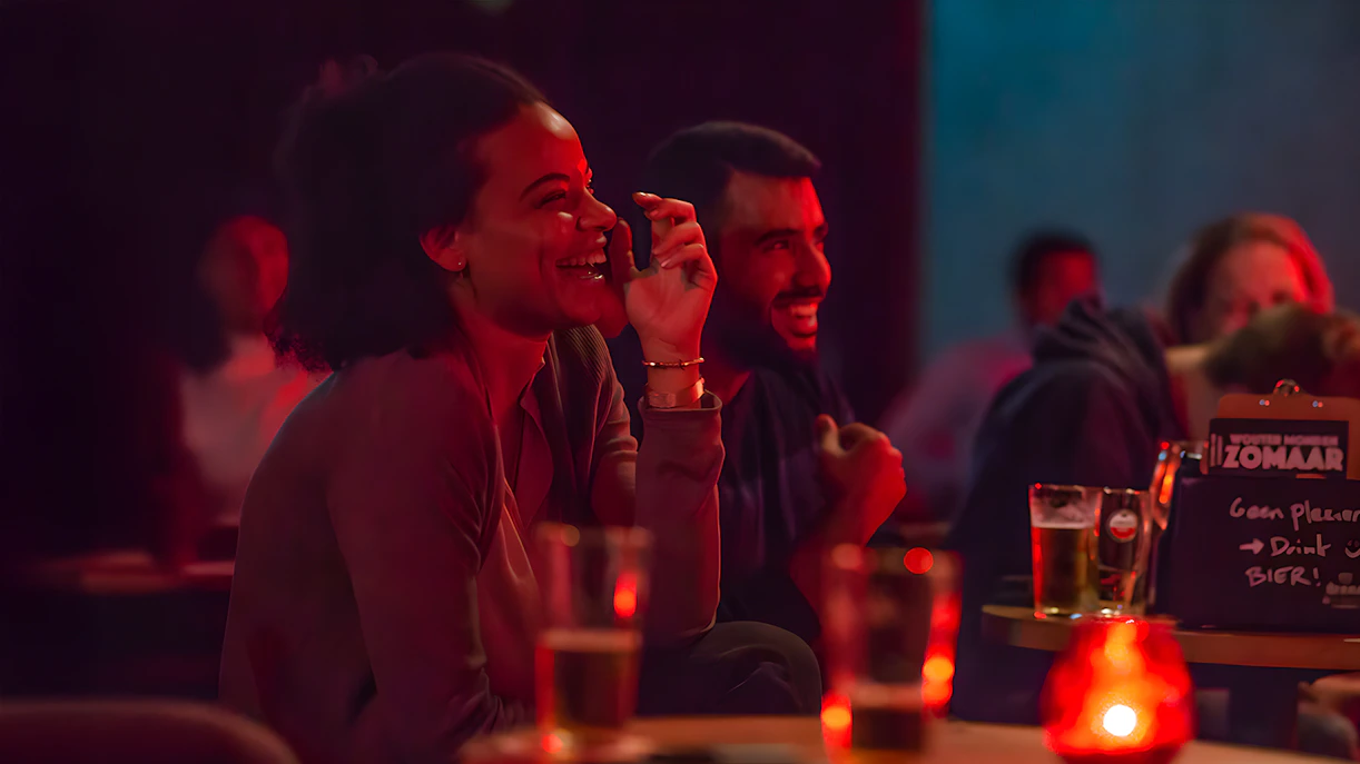 Audience laughing at The Comedy Embassy show with drinks on tables.