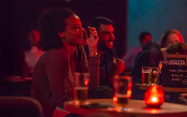Audience laughing at The Comedy Embassy show with drinks on tables.