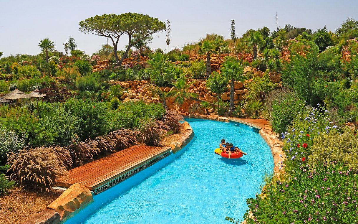 Visitors enjoying a lazy river ride at Zoomarine Portugal surrounded by lush greenery.