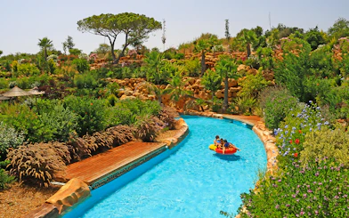 Visitors enjoying a lazy river ride at Zoomarine Portugal surrounded by lush greenery.