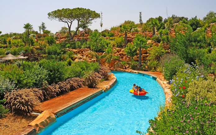 Visitors enjoying a lazy river ride at Zoomarine Portugal surrounded by lush greenery.