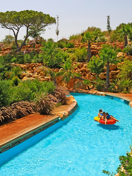 Visitors enjoying a lazy river ride at Zoomarine Portugal surrounded by lush greenery.