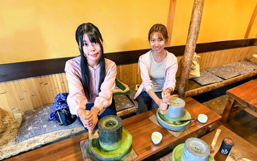 Visitors grinding matcha tea in a traditional workshop on Nara and Kyoto One-Day Bus Tour.