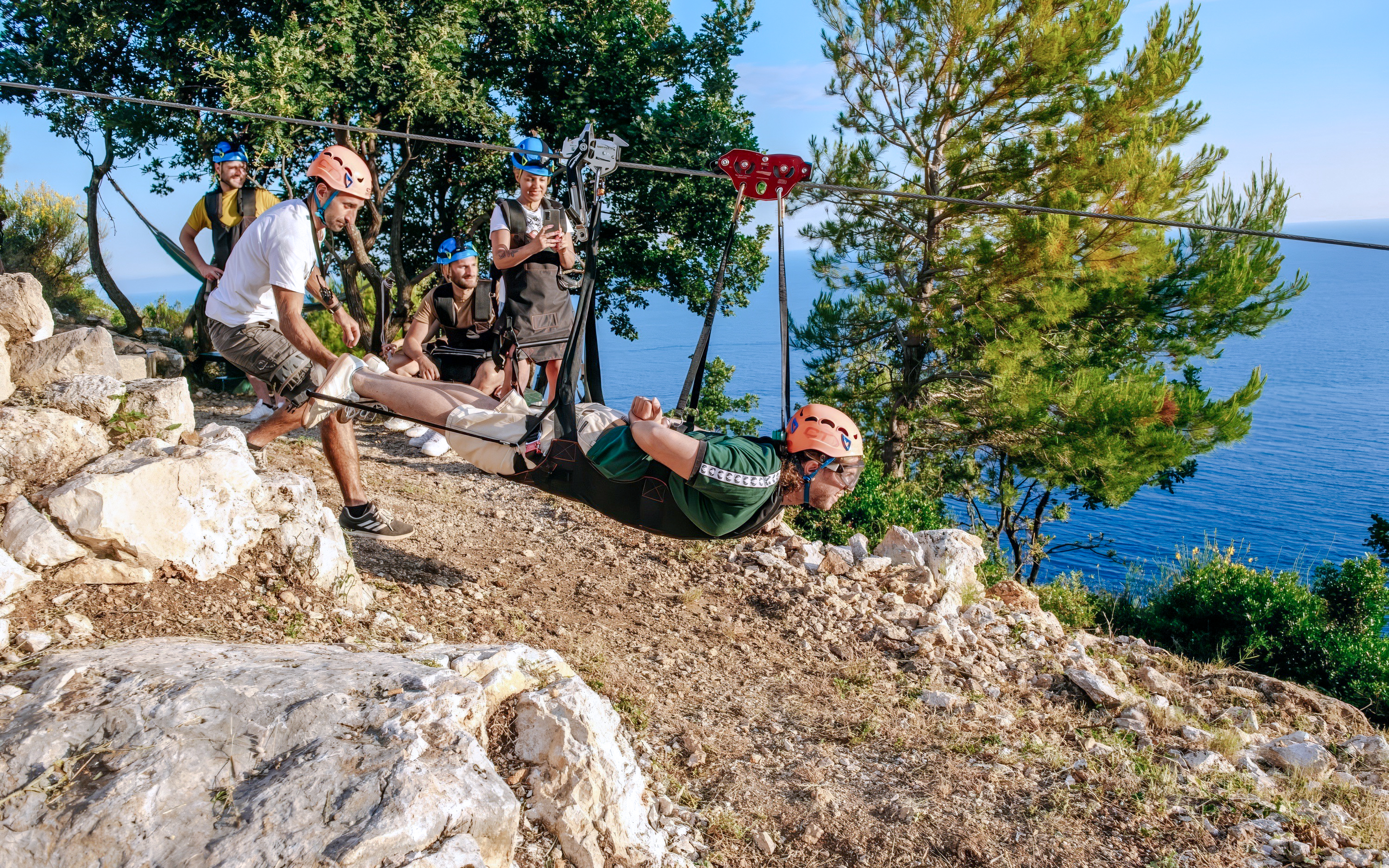 Zip lining over Pasjača Beach, Croatia with ocean view in background.