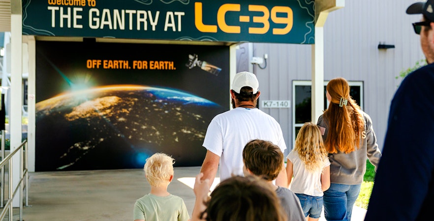 Family entering Gantry at LC-39, space-themed entrance in background.