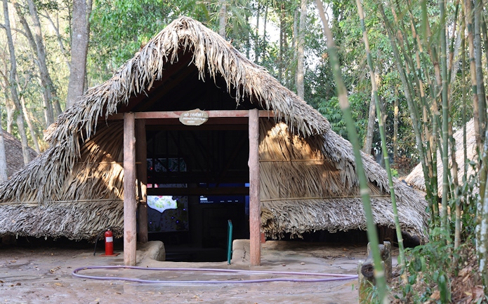 Hut room entrance at Cu Chi Tunnels surrounded by trees.