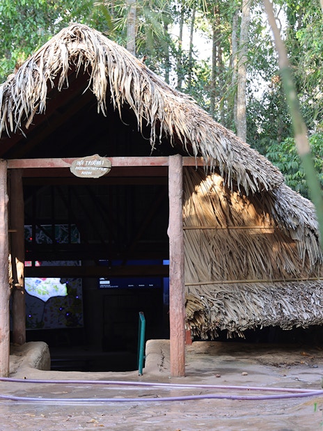 Hut room entrance at Cu Chi Tunnels surrounded by trees.