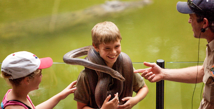 Boy holding a snake at Hartleys Crocodile Adventures, Queensland.