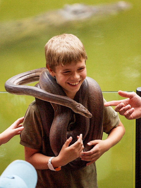 Boy holding a snake at Hartleys Crocodile Adventures, Queensland.