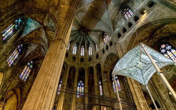 Interior view of Girona Cathedral with stained glass windows and vaulted ceiling.