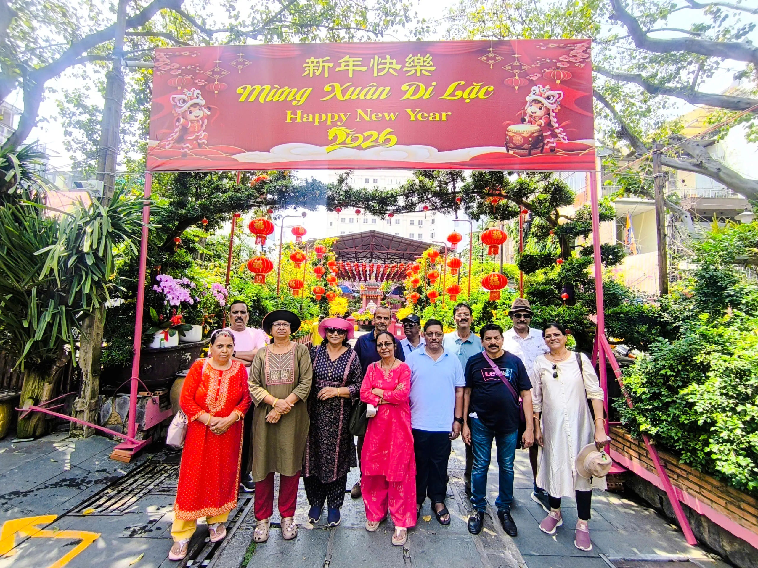 Group of tourists under a festive New Year sign with red lanterns in Ho Chi Minh City.