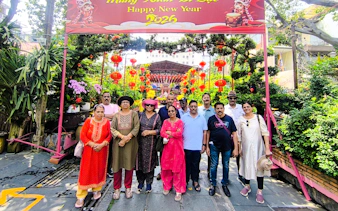 Group of tourists under a festive New Year sign with red lanterns in Ho Chi Minh City.