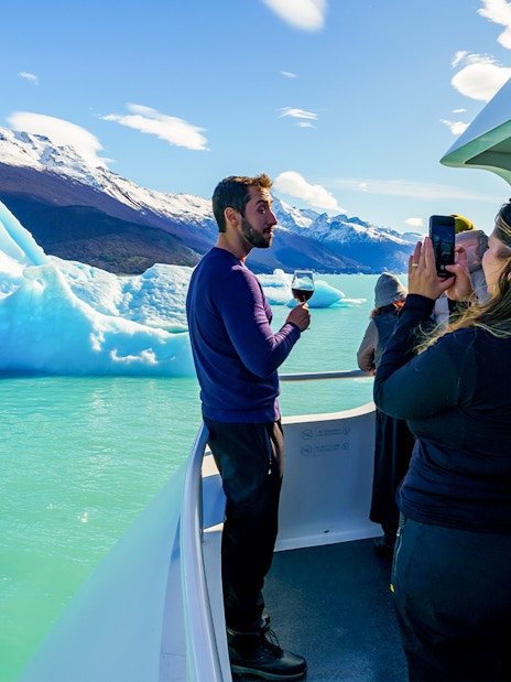 Tourists on a cruise boat photographing icebergs near Perito Moreno Glacier, Argentina.