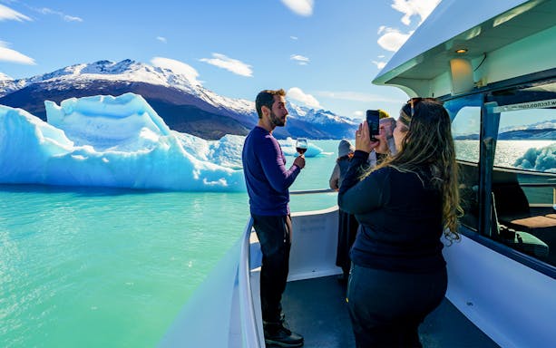 Tourists on a cruise boat photographing icebergs near Perito Moreno Glacier, Argentina.
