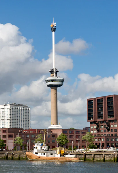 Euromast tower in Rotterdam with surrounding buildings and a boat on the river.