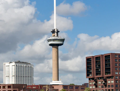 Euromast tower in Rotterdam with surrounding buildings and a boat on the river.