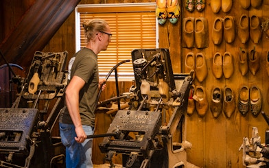 Traditional clog making demonstration with machinery and wooden clogs on display.