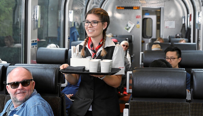 A lady serving food to passenger on Bernina Express in first class.