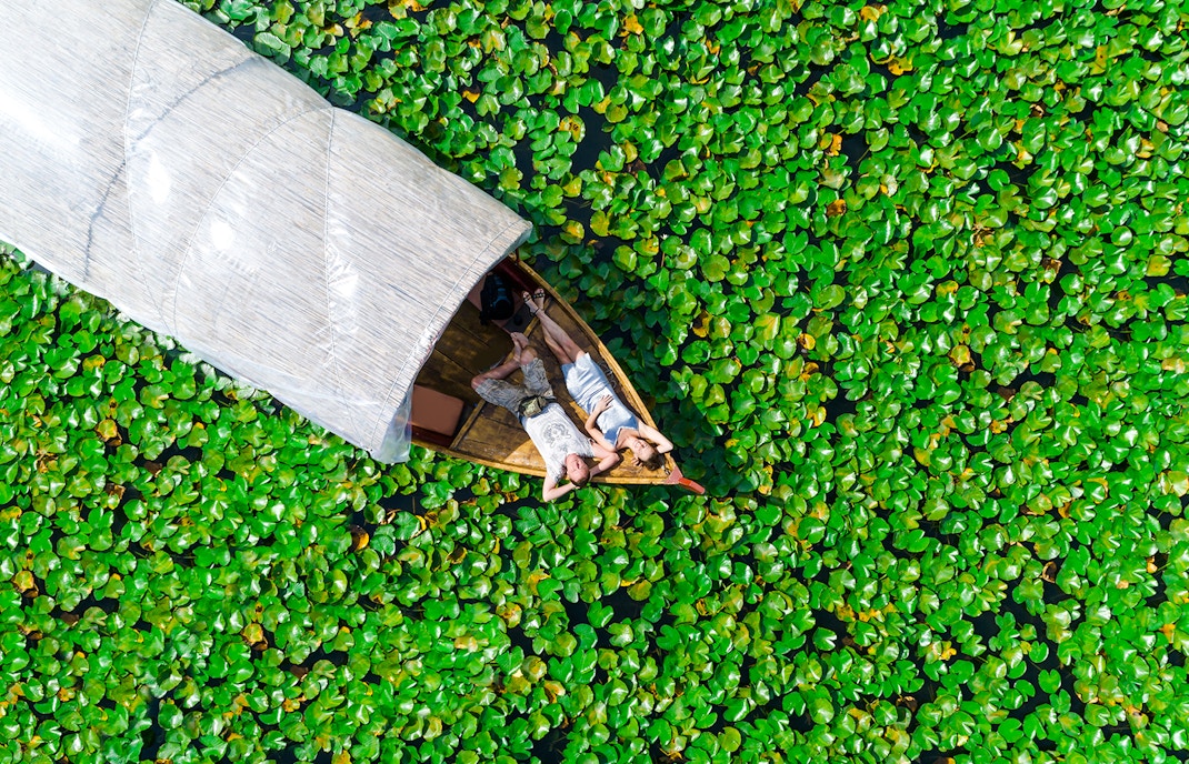 Couple relaxing on a boat surrounded by lily pads on Skadar Lake.