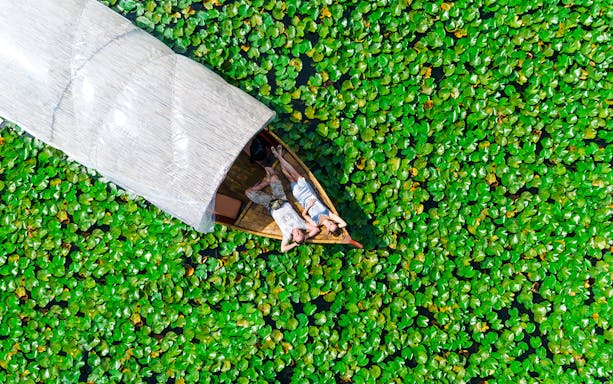 Couple relaxing on a boat surrounded by lily pads on Skadar Lake.