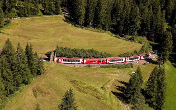 Glacier Express train traveling through lush Swiss countryside with Interrail Pass.
