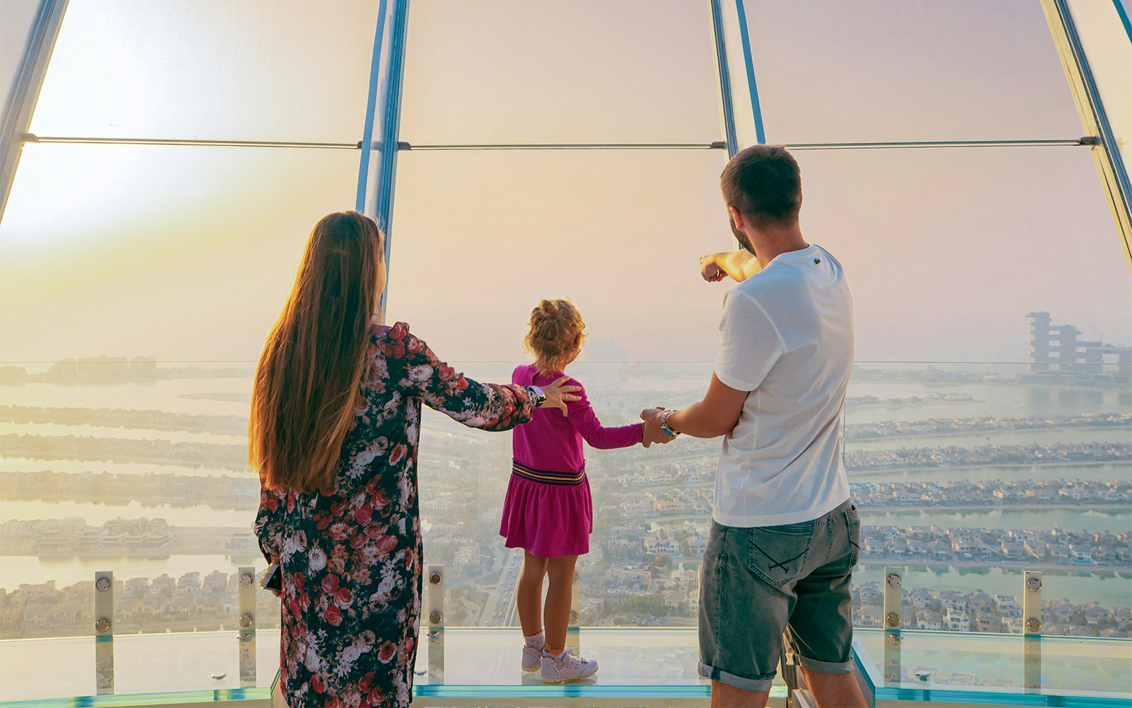 Family enjoying panoramic view of Palm Jumeirah from Dubai Frame observation deck.