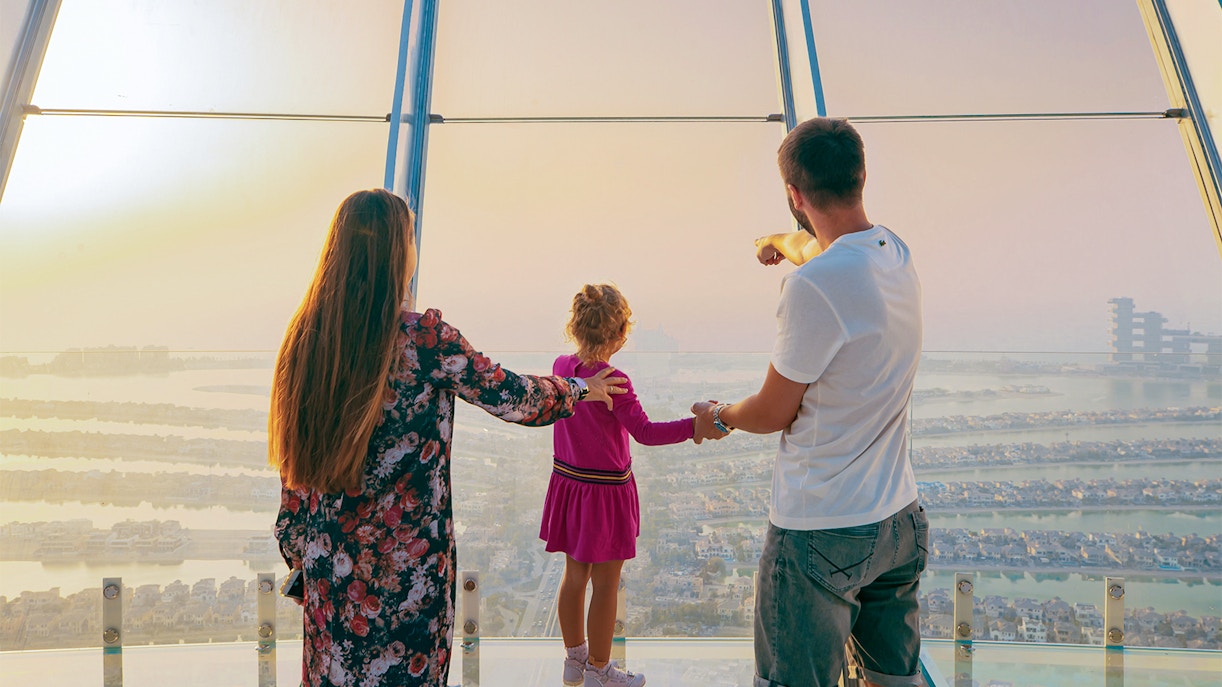 Family enjoying panoramic view of Palm Jumeirah from Dubai Frame observation deck.