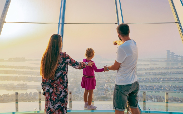 Family enjoying panoramic view of Palm Jumeirah from Dubai Frame observation deck.